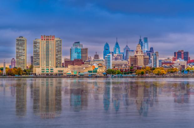 Panoramic photo of the Philadelphia skyline during the daytime with reflection coming off of the Delaware River