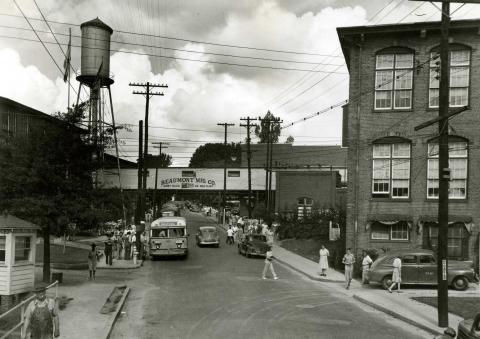 Crowd of people waiting to board a bus, others walking on sidewalks