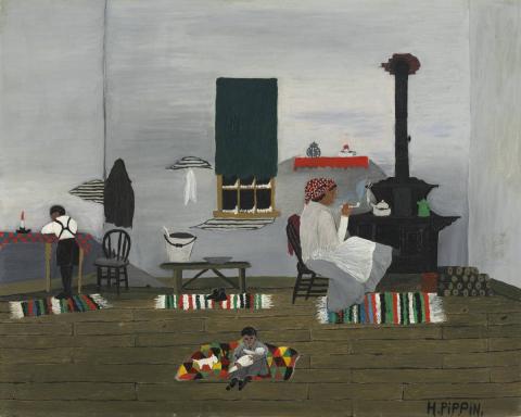Young boy (left) with back turned stands by table with candle while another young child (center) holds baby while sitting on rug. A woman (right) sits beside wood stove with tea kettle.