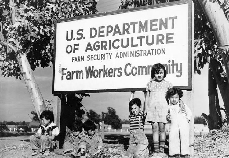 Un grupo de niños en frente del portón de un campamiento de la FSA, El Rio, California, 1941.
