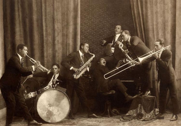 Seven men in suits posed together playing instruments