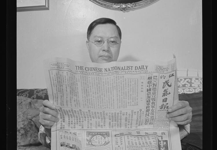 Chinese-American reading thein his home in Flatbush, New York, New York